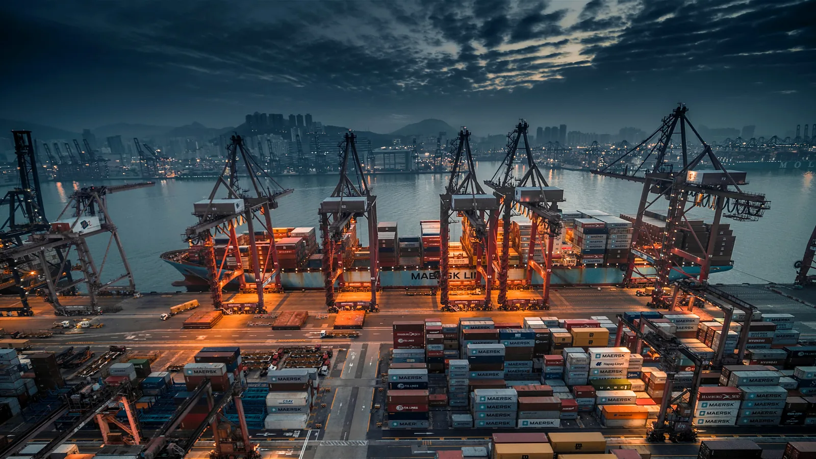 Porto de contêineres ao entardecer com guindastes